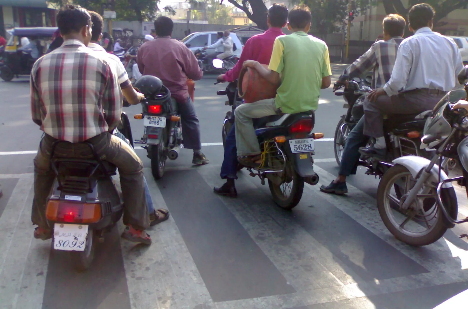 Riders on two-wheelers waiting at a Pune traffic signal